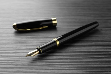 Photo of Stylish fountain pen on black wooden table, closeup