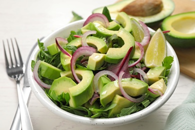 Photo of Delicious avocado salad with arugula on white wooden table