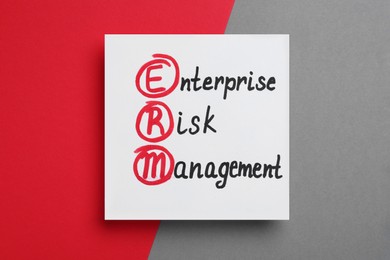 Photo of Paper with ERM abbreviation and its interpretation (Enterprise Risk Management) on color background, top view