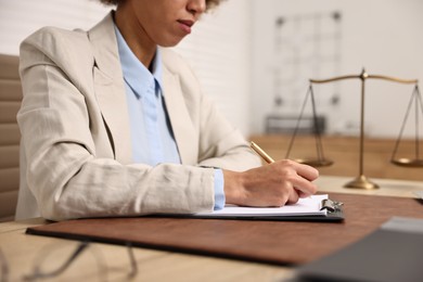 Notary with clipboard writing notes at workplace in office, closeup