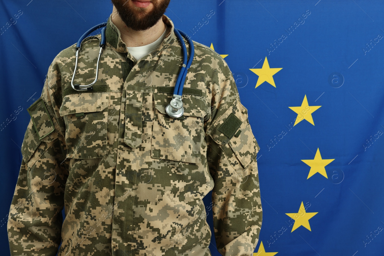 Photo of Man in military uniform with stethoscope against flag of European Union, closeup. Health care concept