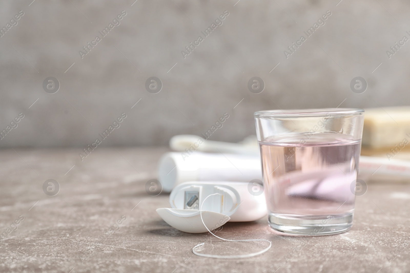 Photo of Glass with mouthwash and dental floss on table. Teeth hygiene