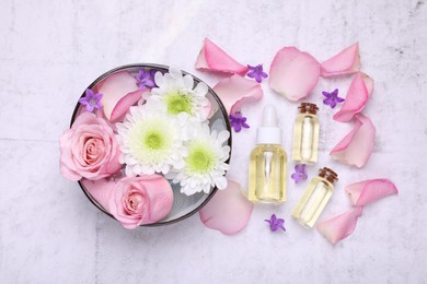 Flat lay composition with bowl of water and beautiful flowers on light table. Spa treatment