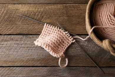 Photo of Soft beige yarn, knitting and metal needles on wooden table, flat lay