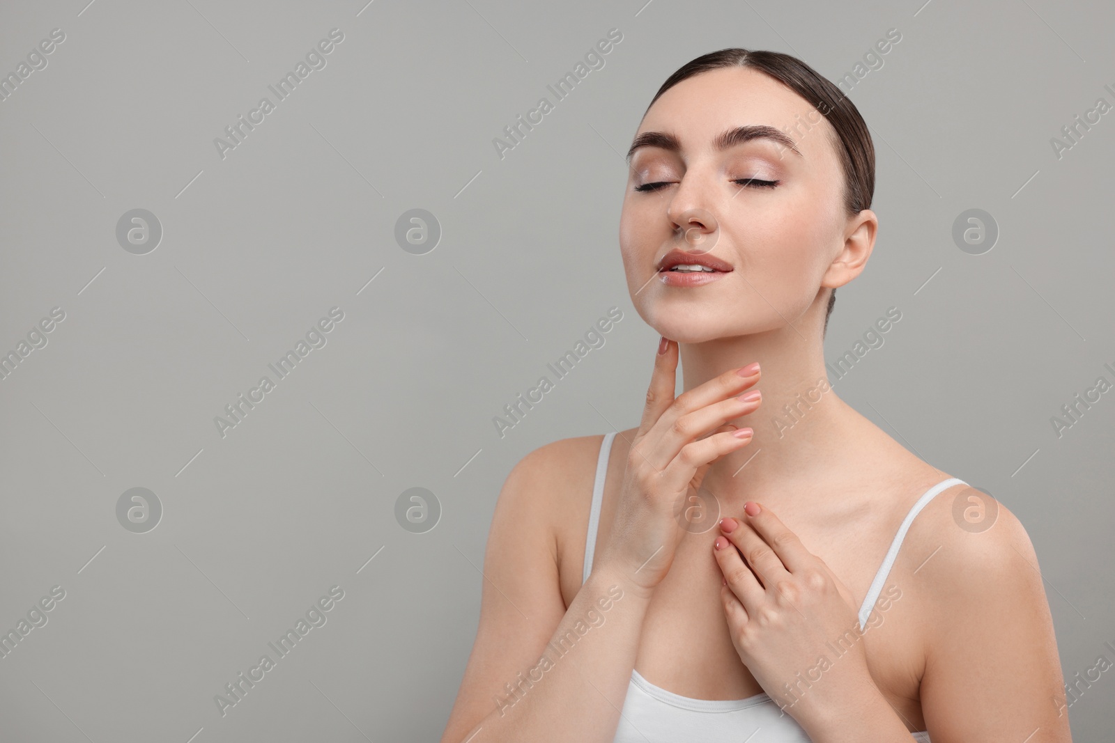 Photo of Beautiful woman touching her chin on grey background. Space for text