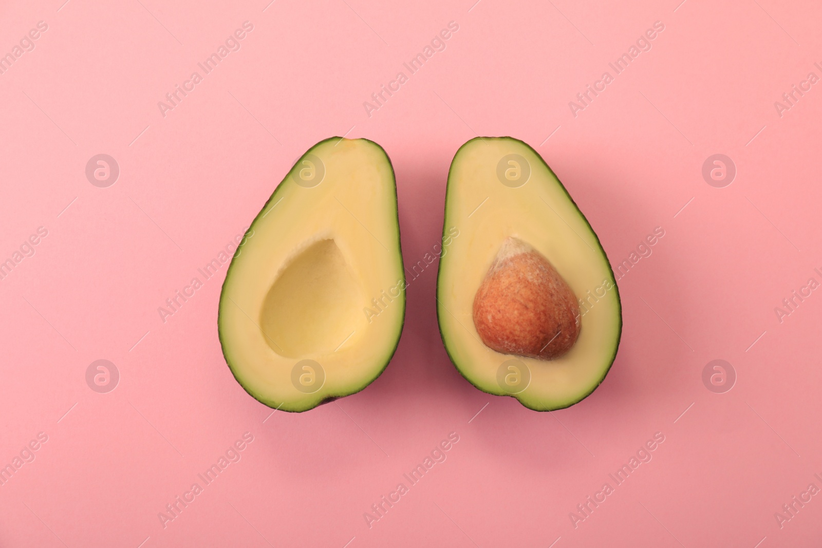 Photo of Halves of delicious avocado on pink background, flat lay