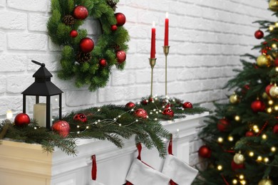 Photo of Beautiful Christmas wreath hanging over fireplace indoors