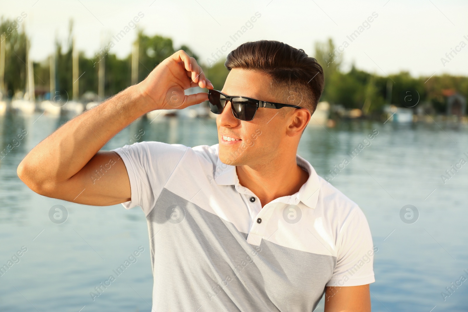 Photo of Handsome man wearing stylish sunglasses near river