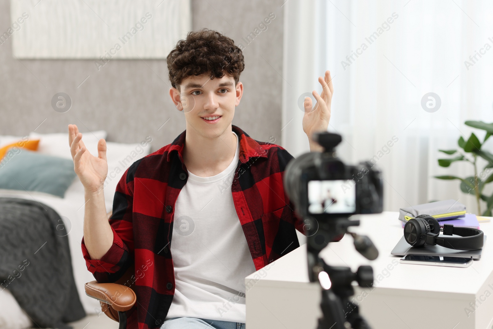 Photo of Smiling teenage blogger explaining something while streaming at home