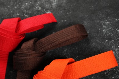 Photo of Colorful karate belts on gray background, flat lay