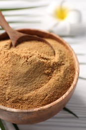 Photo of Coconut sugar and spoon in bowl on white wooden table, closeup