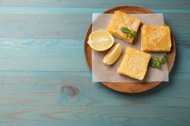 Tasty lemon bars and mint on light blue wooden table, top view. Space for text
