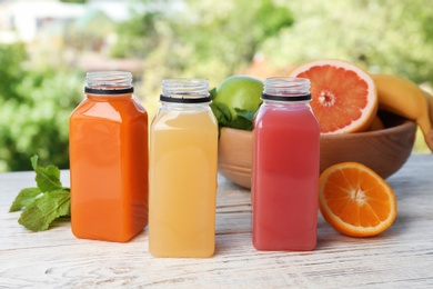 Bottles with tasty juices and ingredients on table