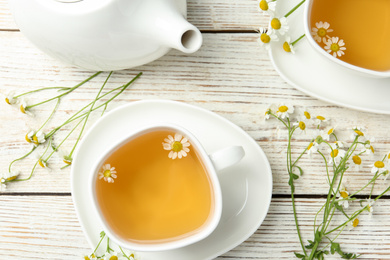 Photo of Flat lay composition with tea and chamomile flowers on white wooden table