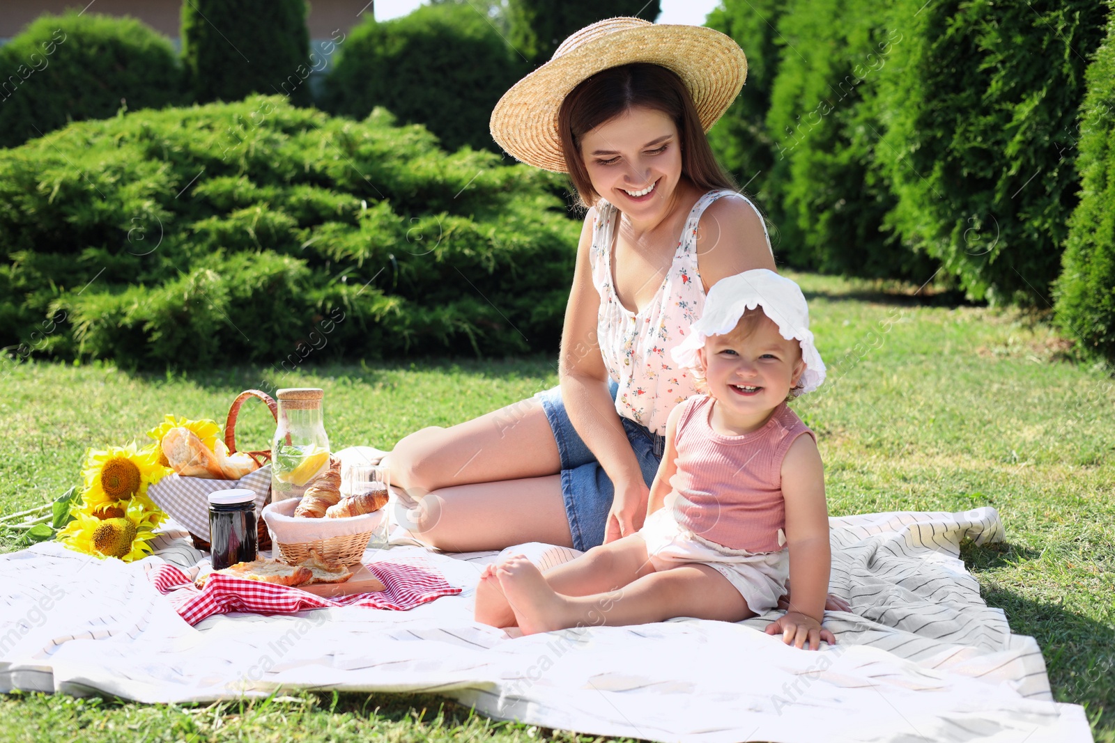 Photo of Mother and her daughter having picnic in garden on sunny day