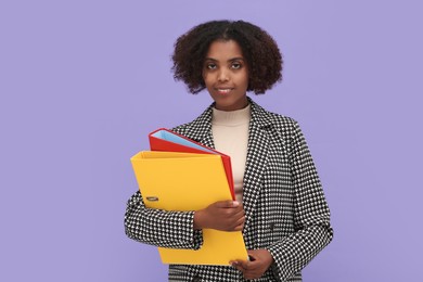 Photo of Smiling African American intern with folders on purple background
