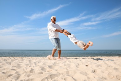 Photo of Cute little boy with grandfather having fun on sea beach