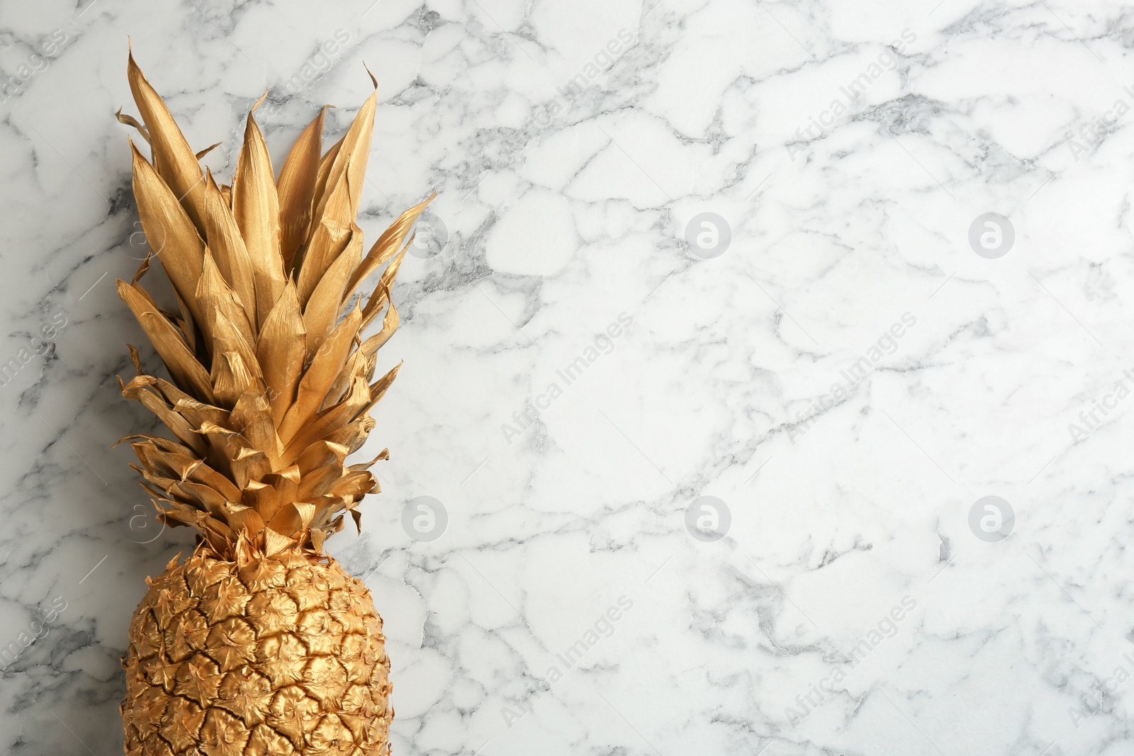 Photo of Golden pineapple on white marble background, top view with space for text. Creative concept