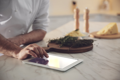 Photo of Chef with tablet cooking at table in kitchen, closeup