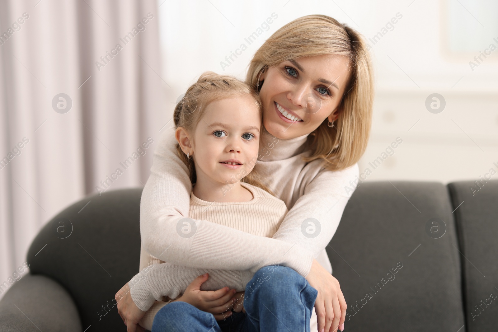 Photo of Happy mother hugging her daughter on sofa at home