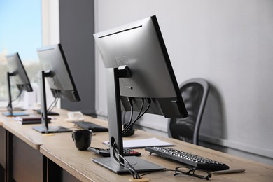 Photo of Open office interior. Modern workplaces with computers near light grey wall