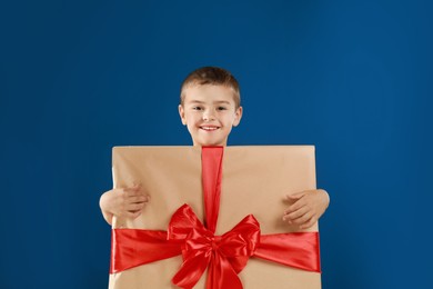 Cute little boy dressed as gift box on blue background. Christmas suit