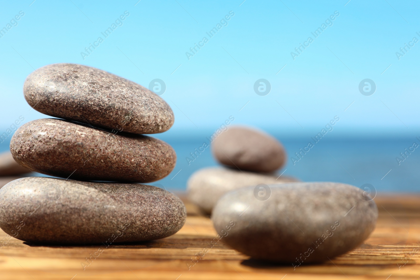 Photo of Stones on wooden table against seascape, space for text. Zen concept