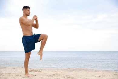 Photo of Muscular man doing exercise on beach, space for text. Body training