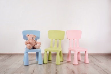 Photo of Different color chairs and toy bear in child room. Space for text