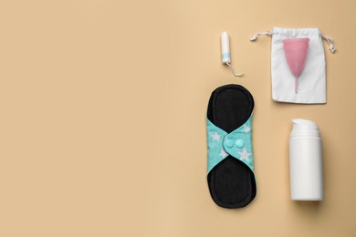 Cloth menstrual pad near other female hygiene products on beige background, flat lay. Space for text