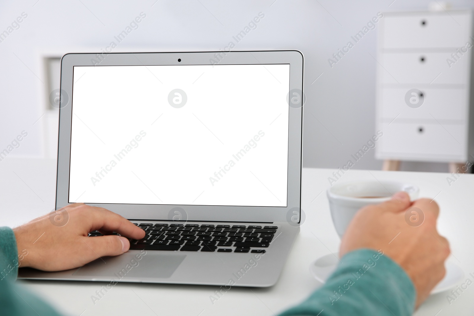 Photo of Young man working with modern laptop at table, closeup. Mockup for design