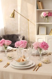 Stylish table setting with beautiful peonies and fabric napkin indoors