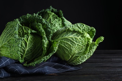 Photo of Fresh ripe savoy cabbages on black wooden table, closeup