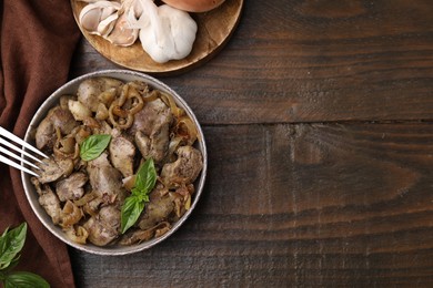 Photo of Delicious fried chicken liver with onion served on wooden table, flat lay. Space for text