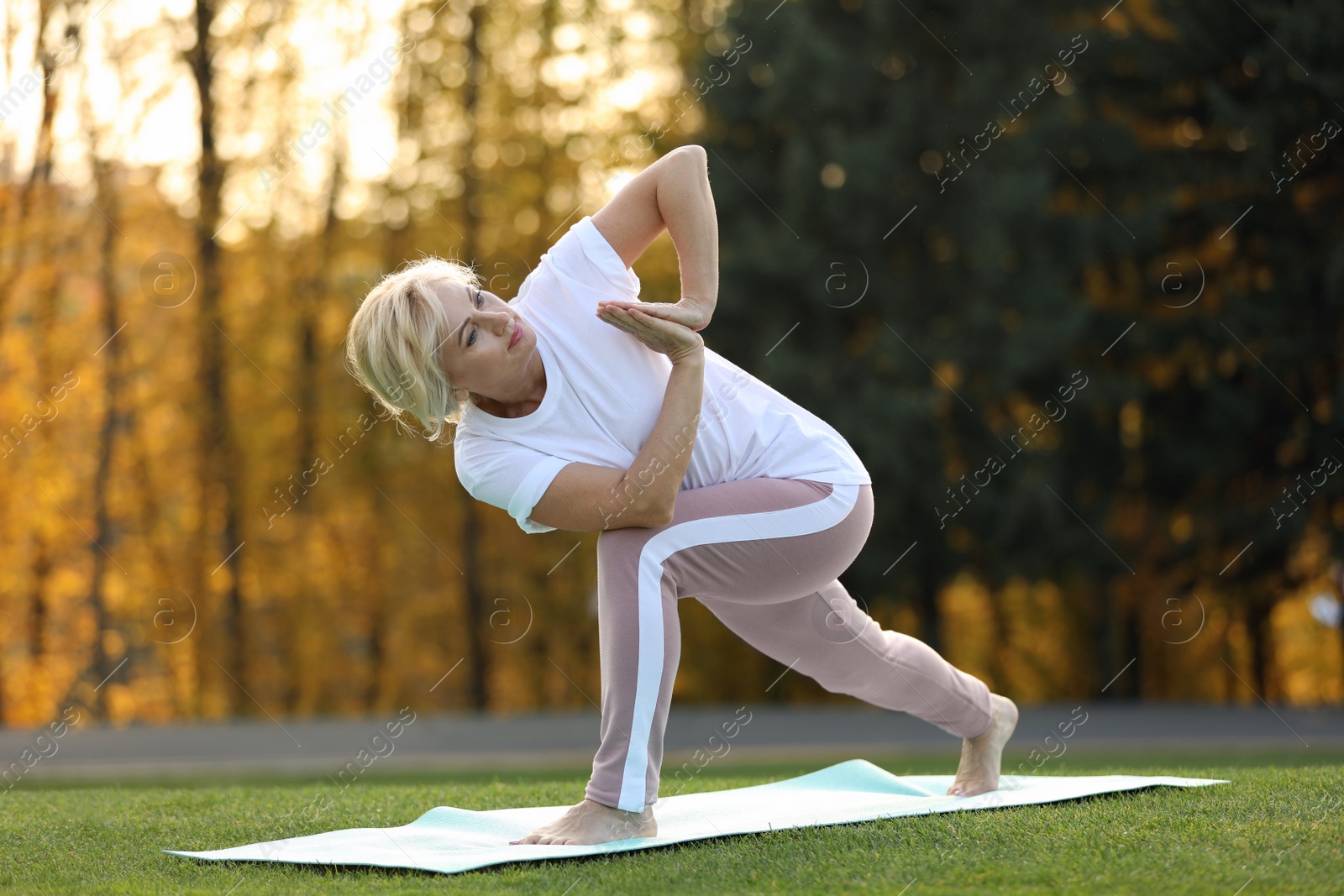Photo of Happy mature woman practicing yoga in park. Active lifestyle