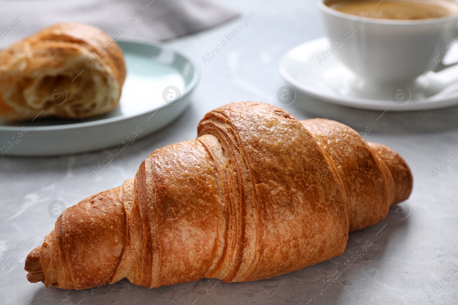 Photo of Tasty fresh croissant on light grey marble table, closeup