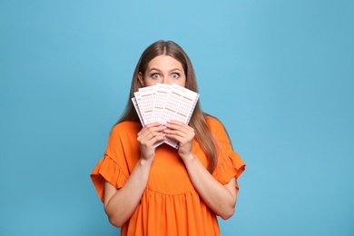 Photo of Portrait of emotional young woman with lottery tickets on light blue background