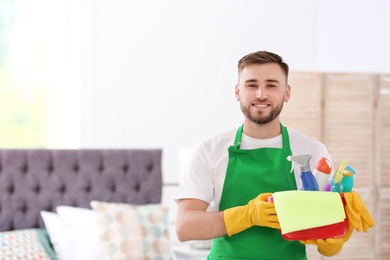 Photo of Man in uniform with cleaning supplies indoors