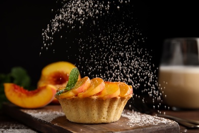 Photo of Decorating delicious peach dessert with powdered sugar on wooden board