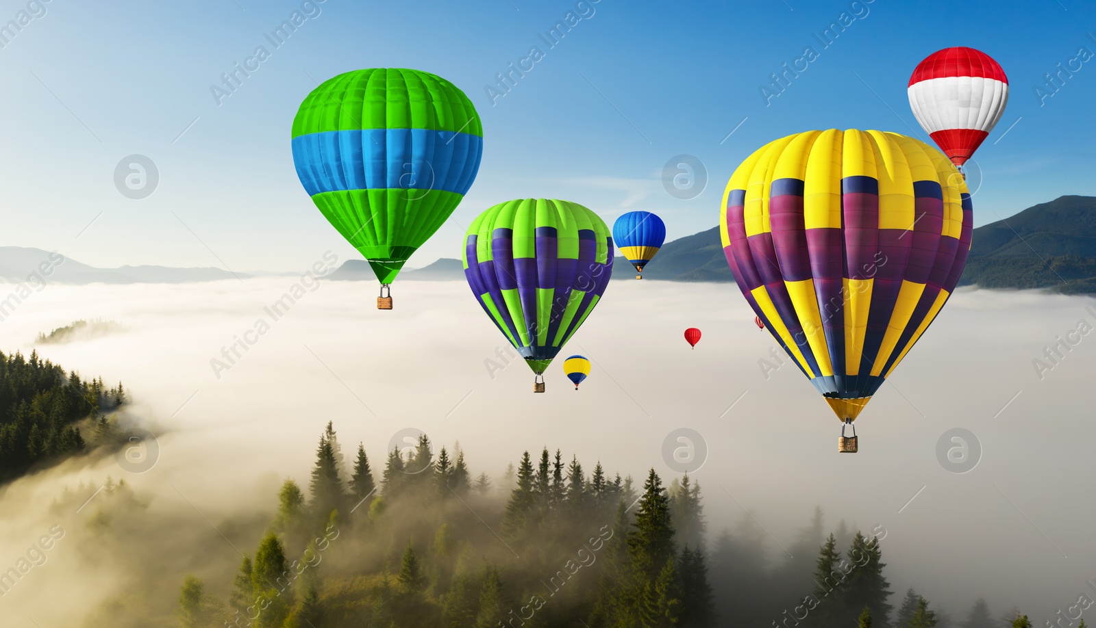 Image of Bright hot air balloons flying over foggy mountains. Banner design