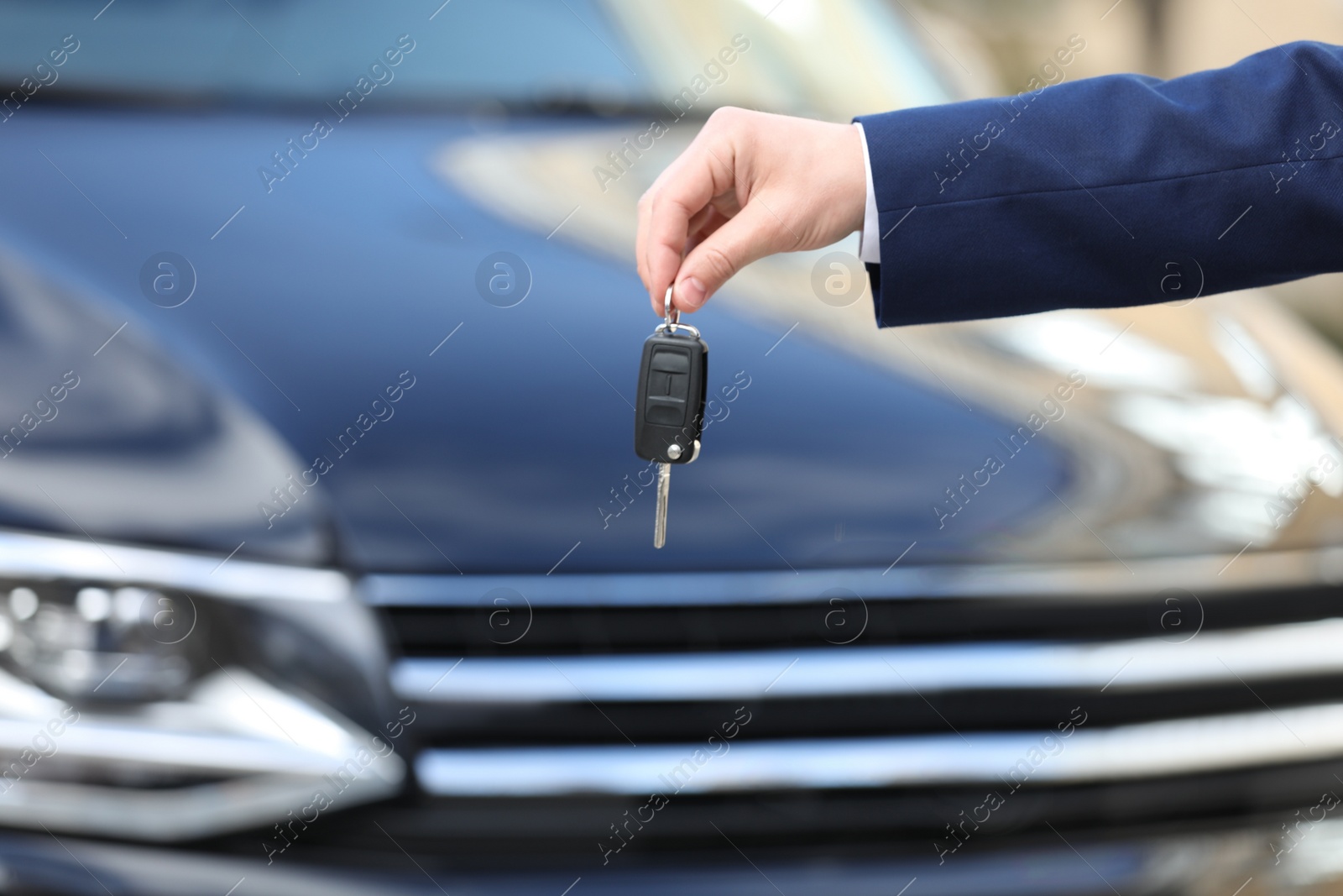 Photo of Man holding key in modern auto dealership, closeup. Buying new car