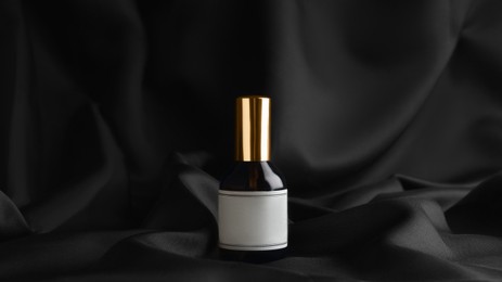 Photo of Luxury bottle of perfume on black silk
