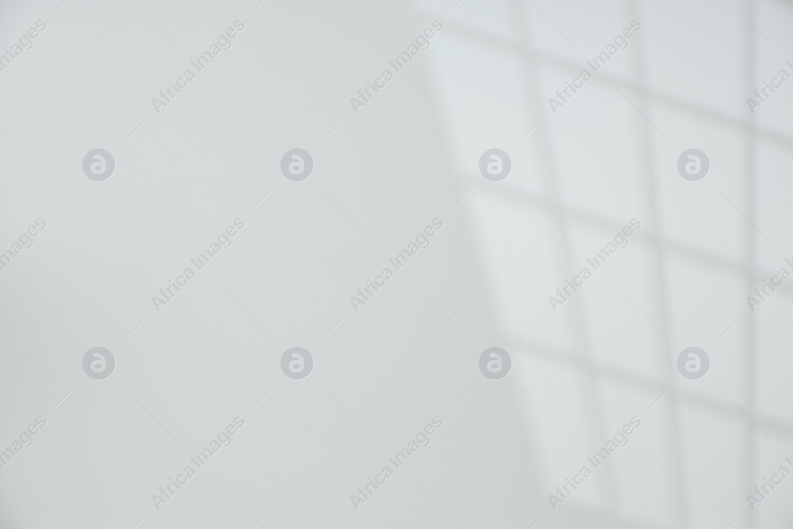 Photo of Light and shadow from window on white wall, space for text