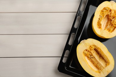 Halves of fresh spaghetti squash in baking sheet on white wooden table, top view with space for text. Cooking vegetarian dish