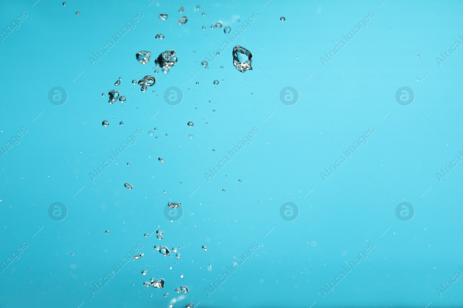 Photo of Air bubbles in water on light blue background