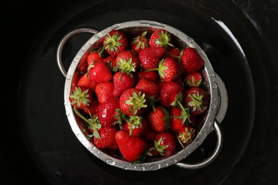 Photo of Metal colander with fresh wet strawberries in sink, top view