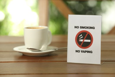 No Smoking No Vaping sign and cup of drink on wooden table outdoors. Space for text