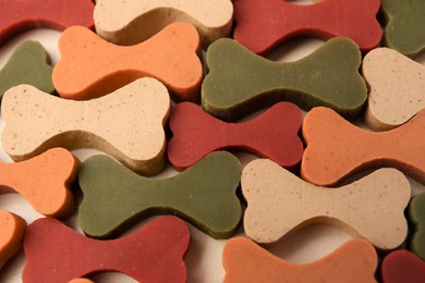 Many bone shaped vitamins for pets on beige background, closeup