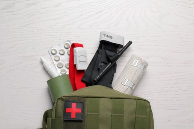 Photo of Military first aid kit, tourniquet, pills and elastic bandage on white wooden table, flat lay