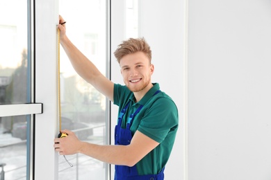 Photo of Service man measuring window for installation indoors